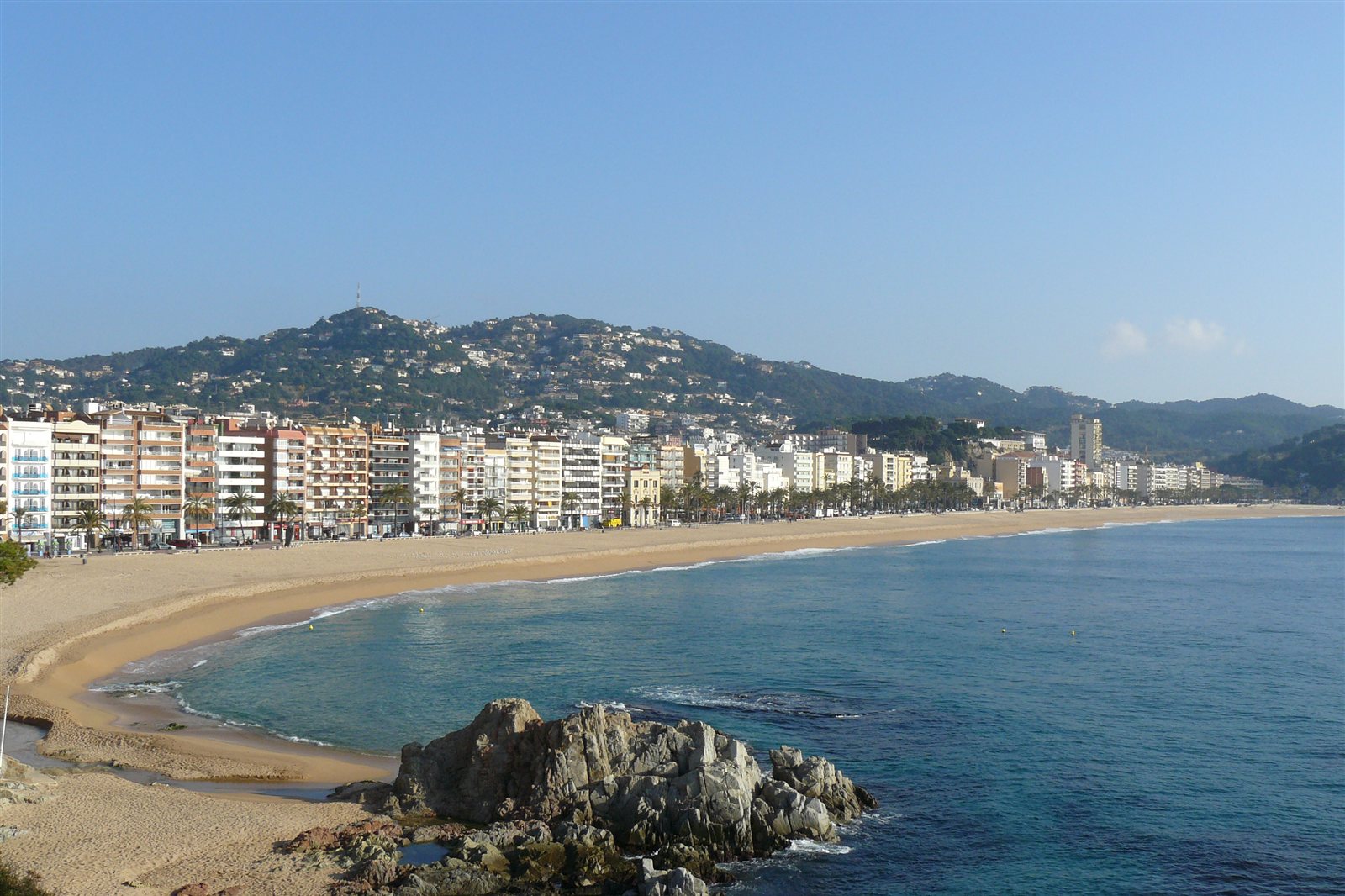 La plage de Lloret de Mar, sur la Costa Brava : sable doré, mer bleue et pins sur les rochers.